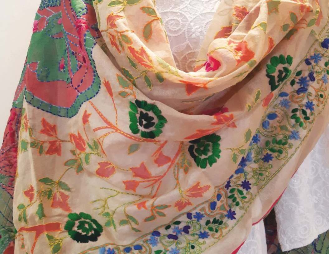 A cream dupatta covered in colourful floral hand embroidery